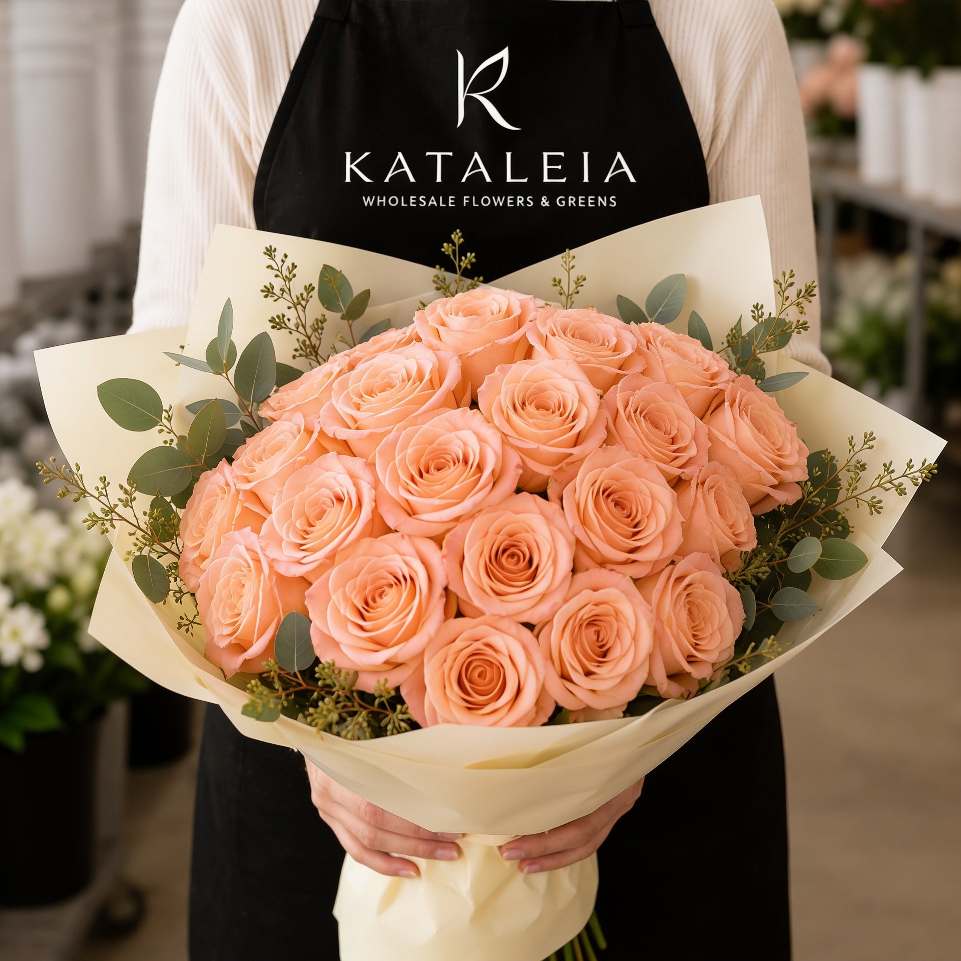Florist holding a wholesale bouquet of fresh peach Alquimia roses with eucalyptus, farm-direct from Kataleia